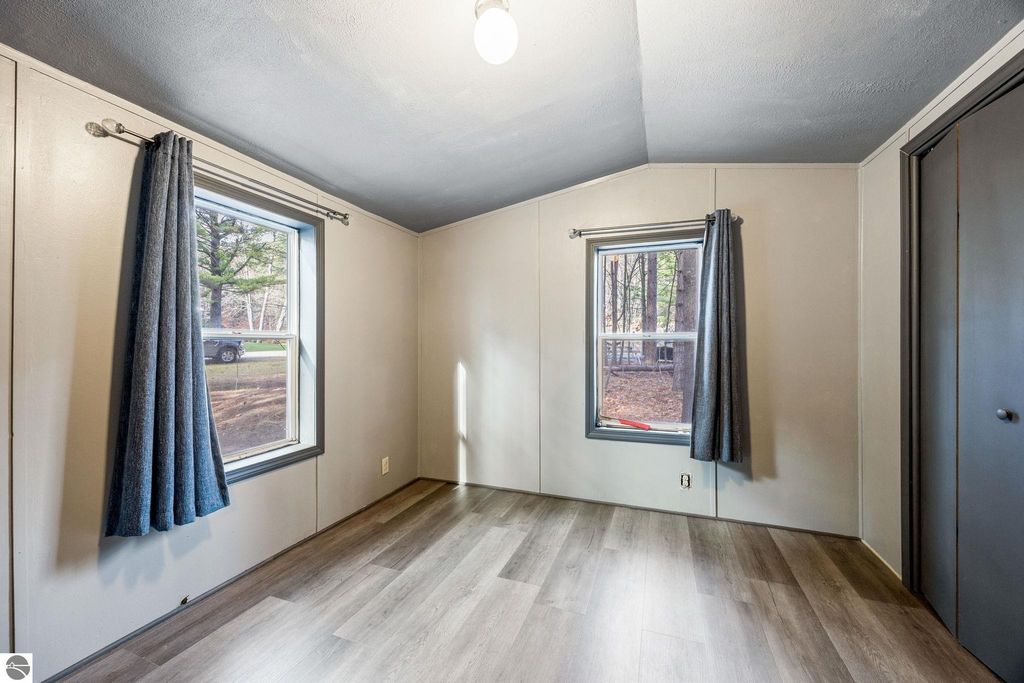 Interior view of a bright, freshly painted room in a home for sale at 8401 Independence Avenue, featuring large windows with curtains, new flooring, and a cozy atmosphere.