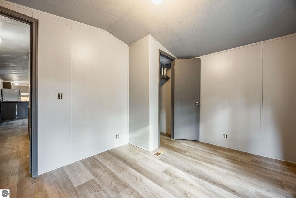 Interior view of a freshly painted room with new flooring, featuring a door leading to a closet and an open doorway to another room, showcasing the move-in ready condition of the home at 8401 Independence Avenue, Cadillac, MI.