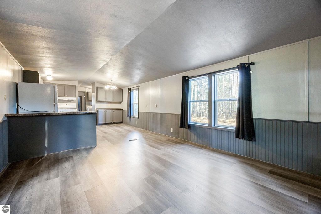 Spacious interior of a move-in ready 3-bedroom home featuring new flooring, modern kitchen appliances, and large windows providing natural light, located at 8401 Independence Avenue, Cadillac, MI.