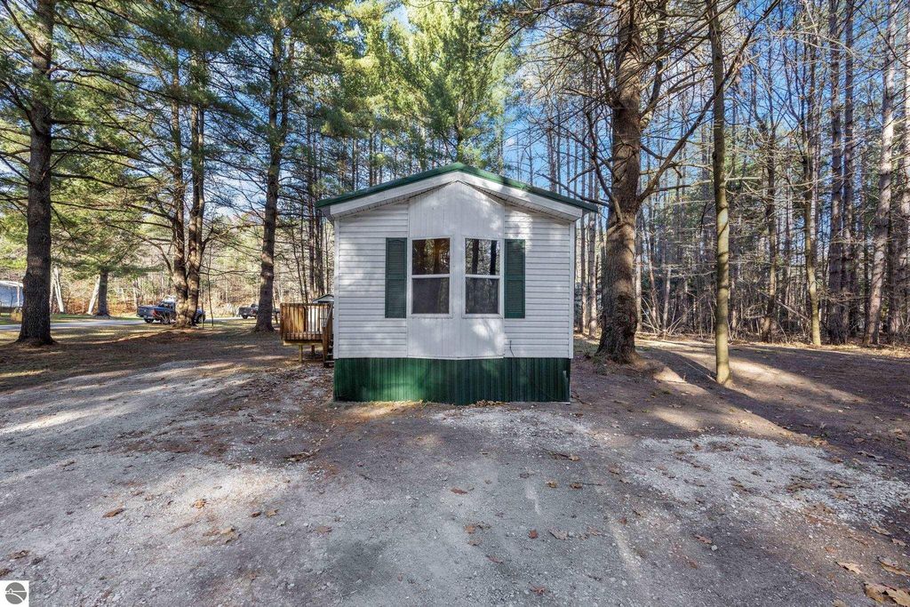 Move-in ready 3-bedroom, 1-bathroom home at 8401 Independence Avenue, Cadillac, MI, featuring a newer metal roof, surrounded by trees on a spacious lot.