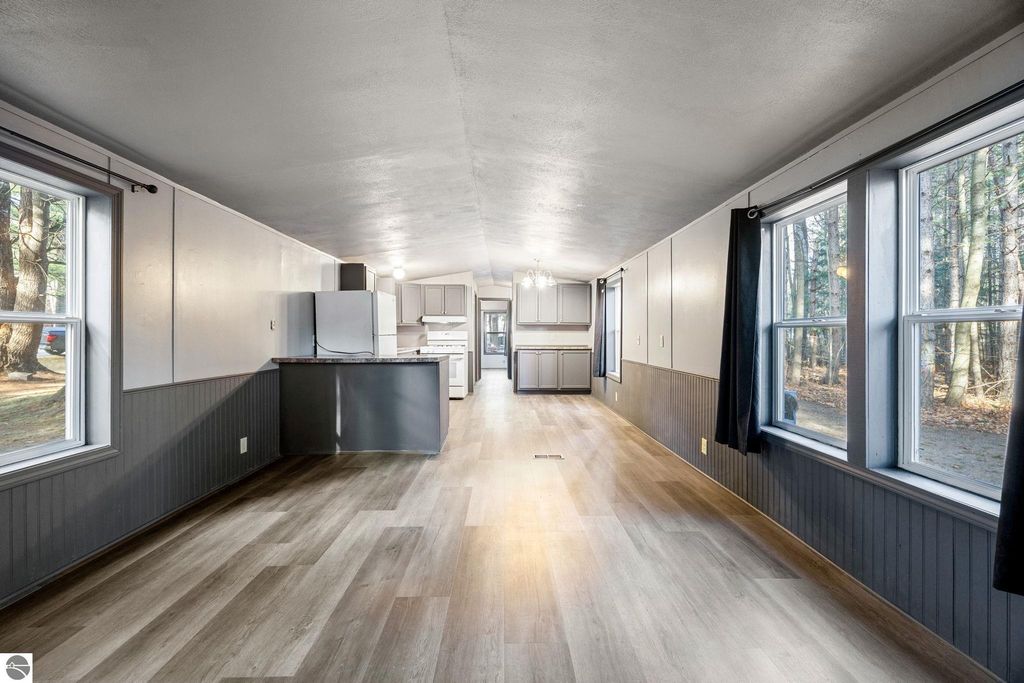 Interior view of a modern, move-in ready home featuring an open layout, new flooring, and a kitchen area with appliances, large windows providing natural light, and a cozy atmosphere in Cadillac, MI.