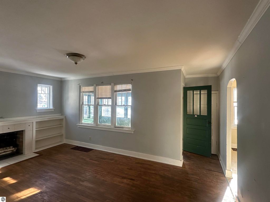Cozy living room of a 2-bedroom home at 110 W State Street, featuring hardwood flooring, built-in shelves, and a green entry door, highlighting classic character and inviting ambiance.