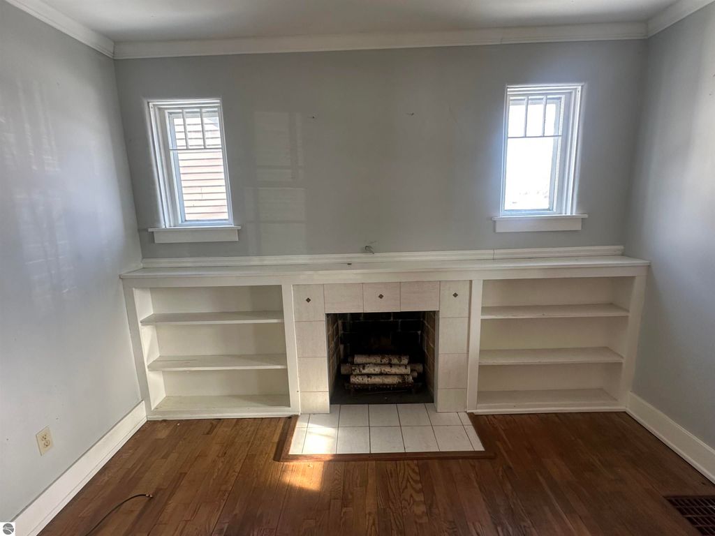 Cozy interior of a 2-bedroom home in Clare, MI, featuring built-in shelves, a fireplace, and natural light from windows.