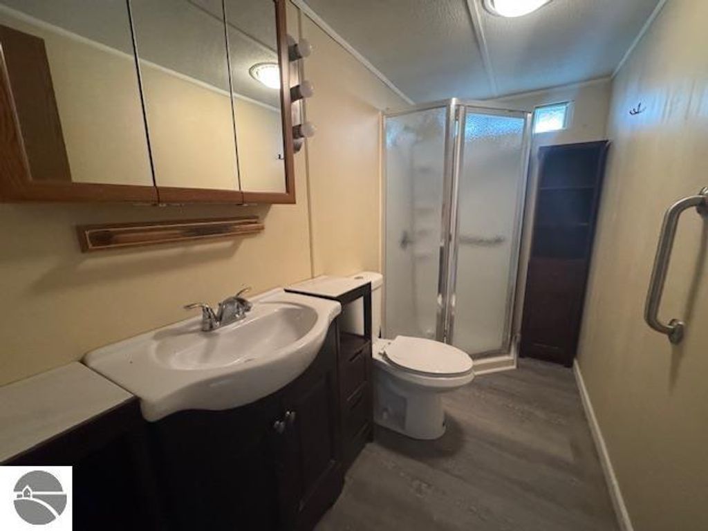 Bathroom interior featuring a sink with modern faucet, shower stall, toilet, and storage cabinet, showcasing the updated amenities in the Lake City home listing at 2520 S Blodgett.