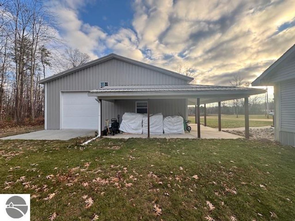 60x30 pole barn with garage door and covered porch, surrounded by grass and trees, near Lake City, MI.