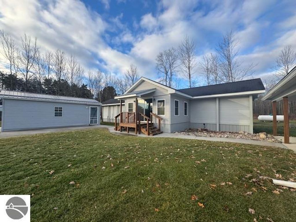 Well-maintained 3-bedroom, 1-bath home with a large front porch, surrounded by grassy yard and trees, featuring nearby garage and shed, located on 2.5 acres in Lake City, MI.
