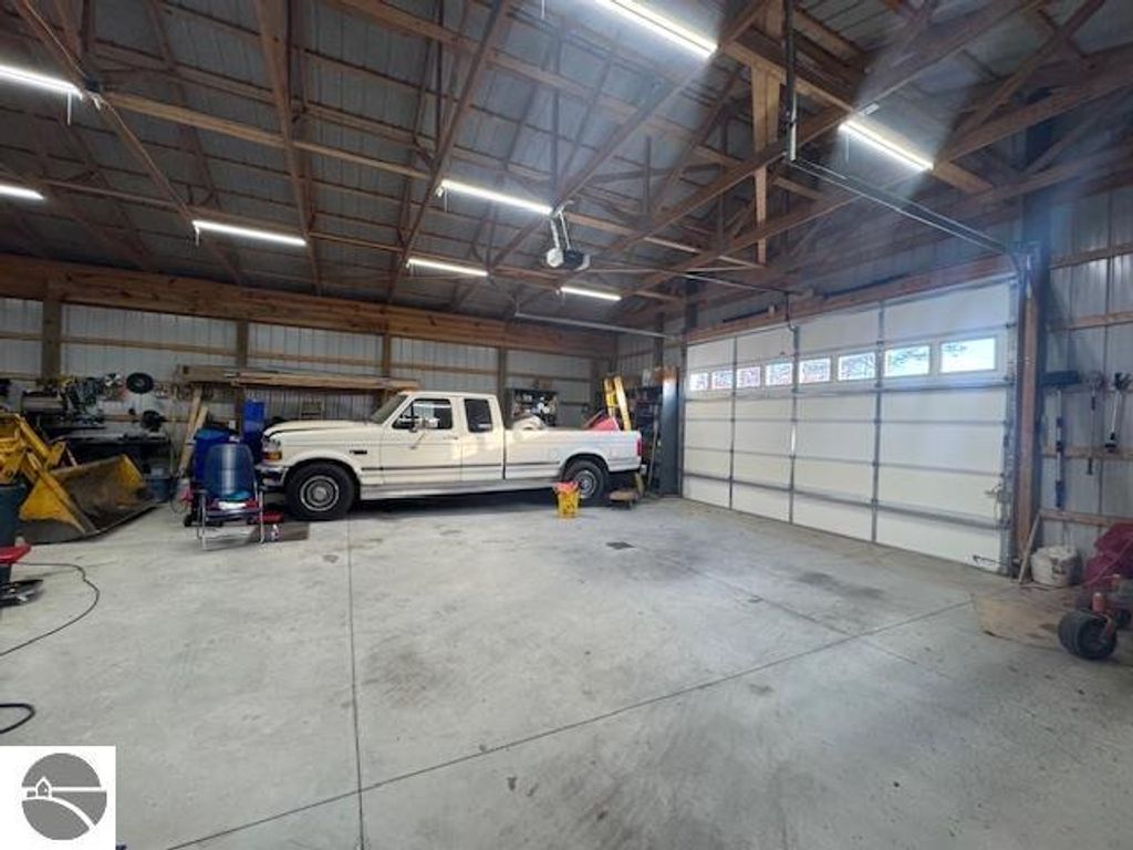 Spacious pole barn interior featuring a white pickup truck, workbench, and ample storage space, highlighting the property at 2520 S Blodgett, Lake City, MI.