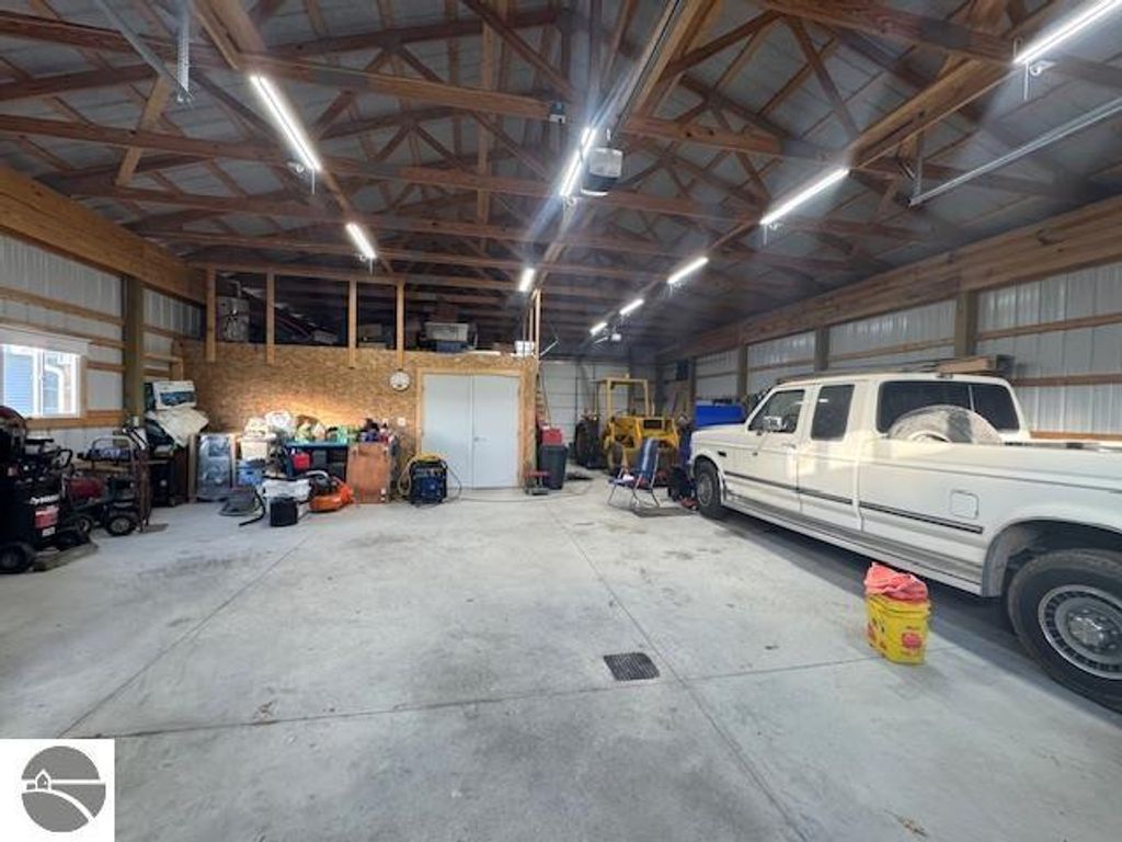 Spacious 60x30 pole barn interior with white pickup truck, storage equipment, and organized workspace, showcasing ample storage potential on property at 2520 S Blodgett, Lake City, MI.