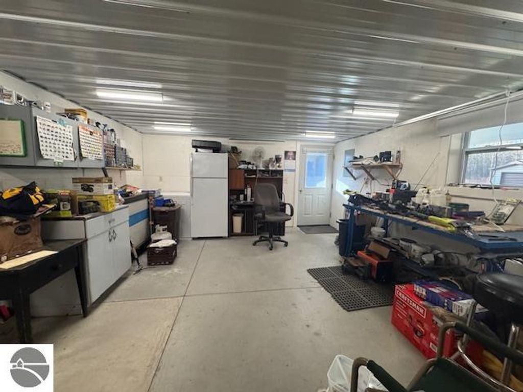 Interior view of a well-organized workshop featuring a refrigerator, workspace with tools, and storage shelves, part of the property at 2520 S Blodgett, Lake City, MI, including features for a workroom and storage on 2.5 acres.