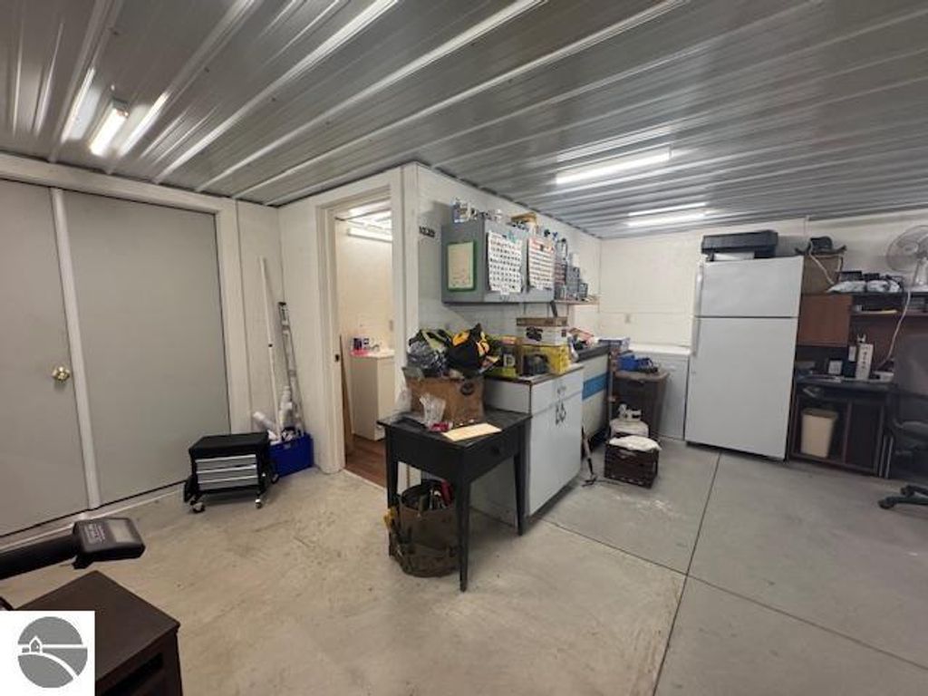 Interior of a well-organized pole barn with storage, workbench, and refrigerator, showcasing functional space for projects and storage needs.