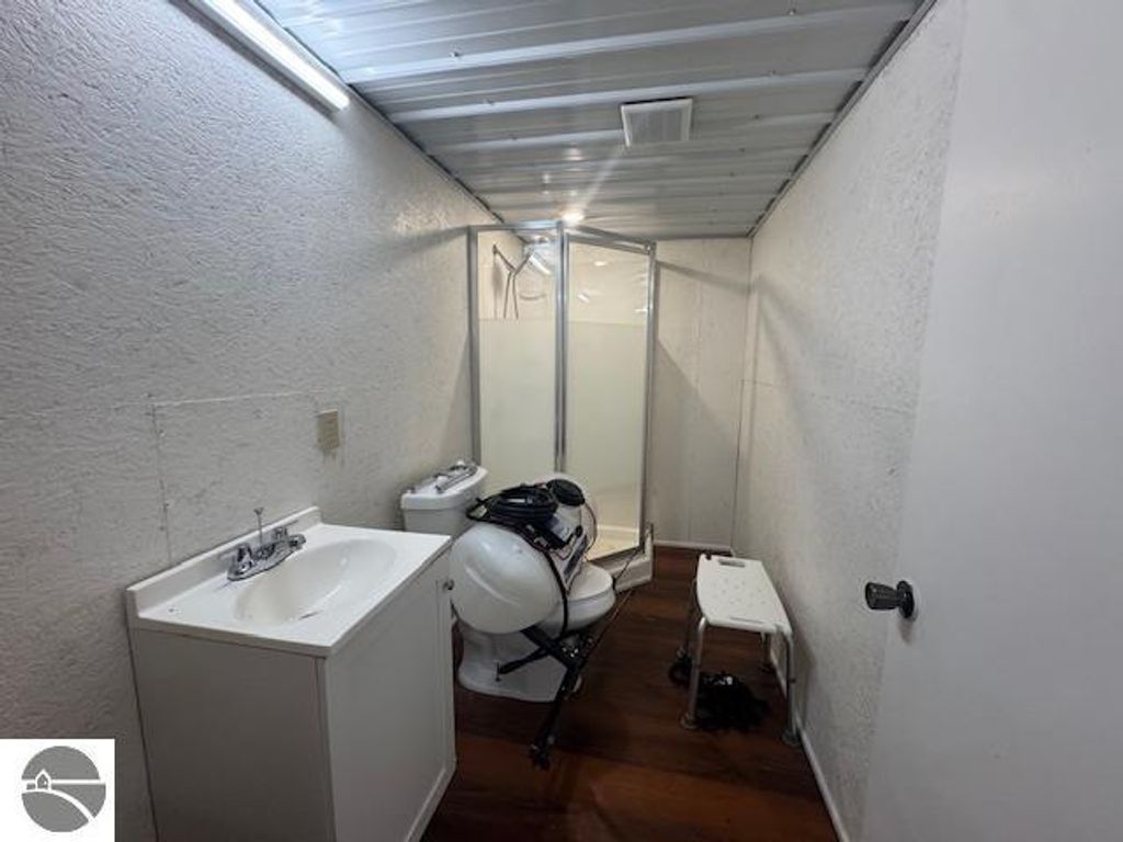 Interior view of a bathroom featuring a sink, toilet, and shower stall, with a white and wood design, showcasing space and functionality for the Lake City property listing.