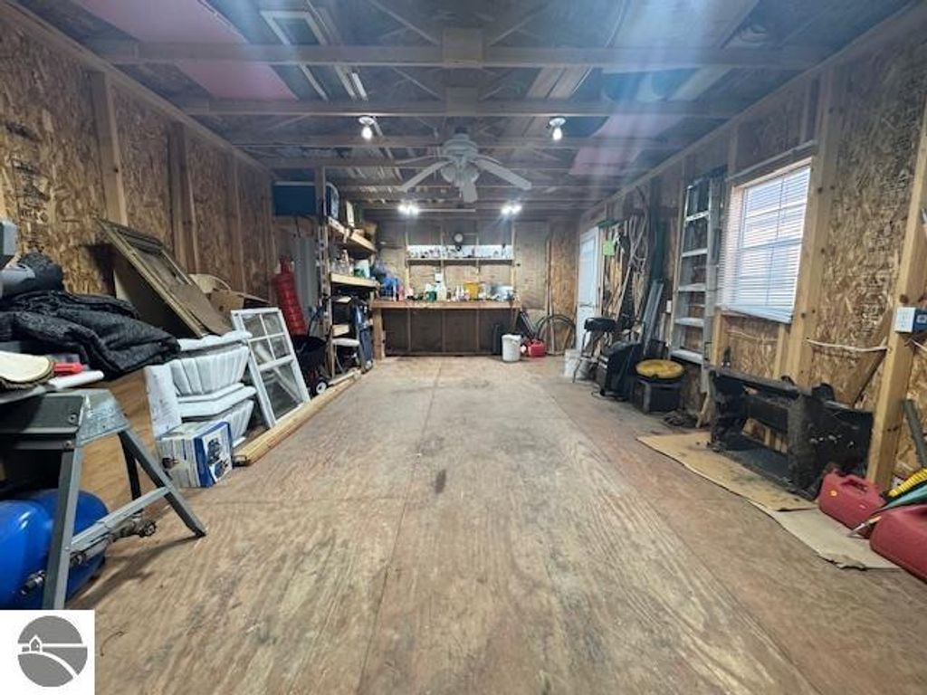 Interior of a spacious pole barn with wooden walls, showcasing a work area filled with tools, shelves, and storage items, emphasizing the property's ample storage potential at 2520 S Blodgett, Lake City, MI.