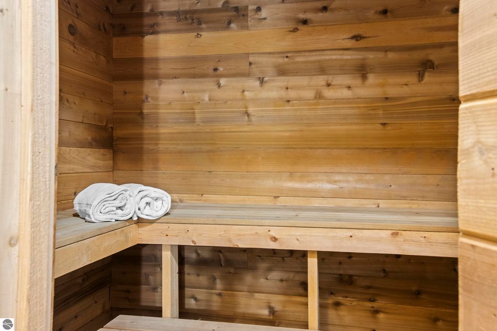 Sauna interior with wooden walls and benches, featuring neatly rolled white towels, reflecting luxury and relaxation amenities at 10371 Deerpath North, Traverse City, MI.