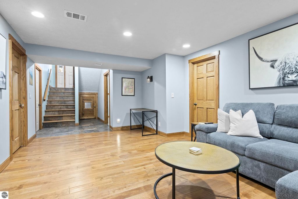 Cozy interior living space at 10371 Deerpath North, featuring hardwood flooring, modern couch with pillows, decorative wall art, and staircase leading to upper levels.