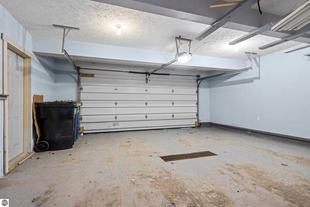 Garage interior of 10371 Deerpath North, featuring a spacious layout with a garage door, light fixture, and a trash can, highlighting the property's amenities.