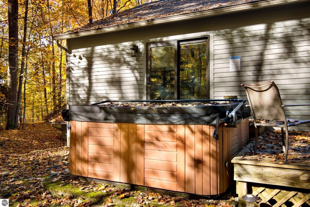 Hot tub on a deck surrounded by autumn foliage at 10371 Deerpath North, Traverse City, MI, highlighting outdoor relaxation and luxury living.