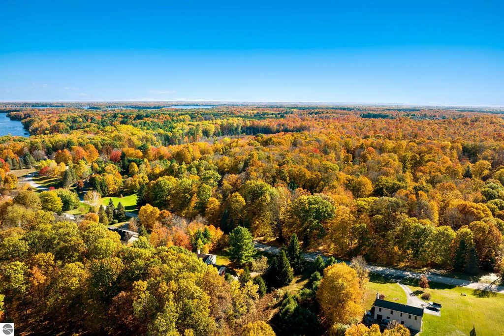 Aerial view of vibrant autumn foliage surrounding 10371 Deerpath North, Traverse City, MI, showcasing wooded landscape and nearby Long Lake.