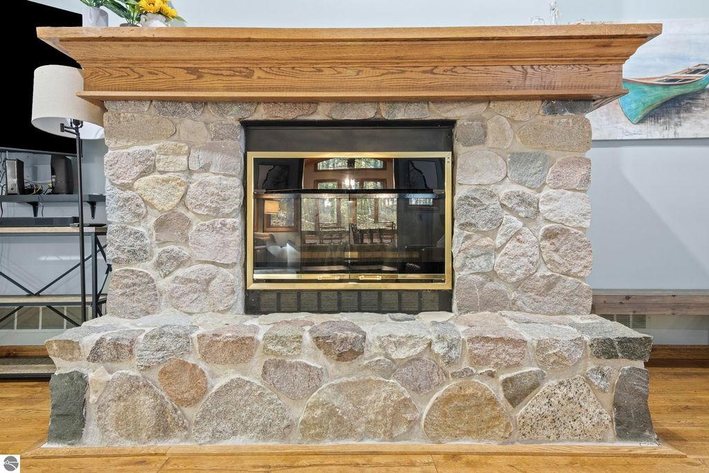 Stone fireplace with wooden mantel, surrounded by a cozy living space, showcasing modern decor and natural light.
